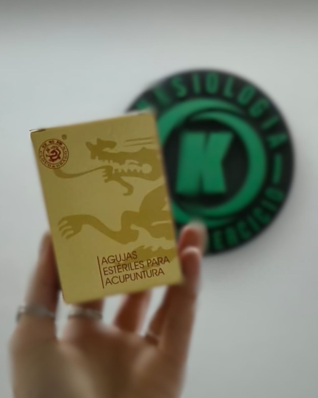Caja de agujas estériles de un solo uso para acupuntura junto al logo de Kinesiología Salud y Ejercicio